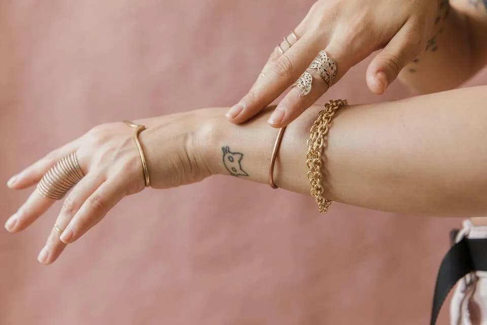 Person wearing gold bracelets and rings designed for sensitive skin on wrist and hand