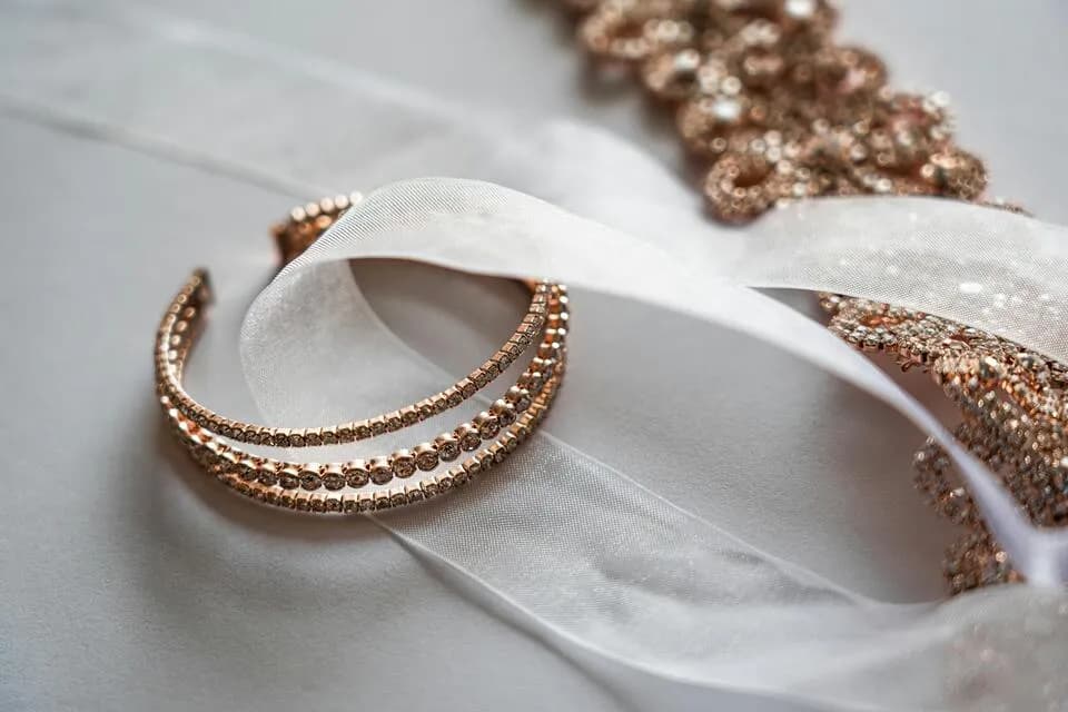 Rose gold crystal bangles placed on soft white ribbon with elegant jewelry details.