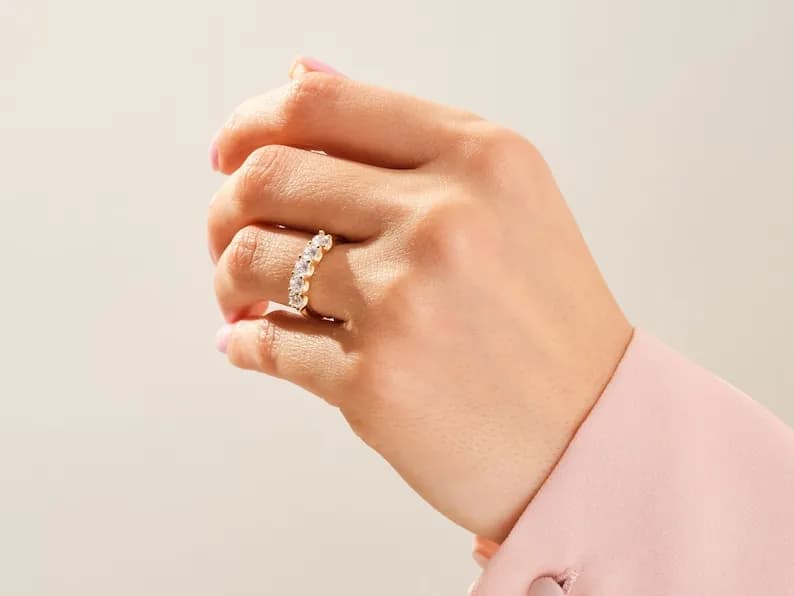 Gold band ring with a row of clear round stones.