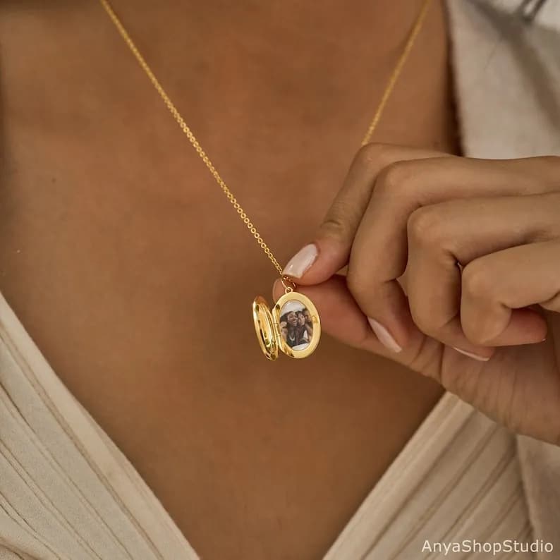 Gold chain necklace with an oval locket pendant, open showing a photo inside.