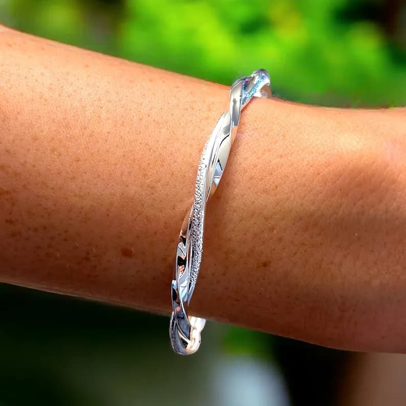 A silver twisted bangle bracelet with a textured finish.