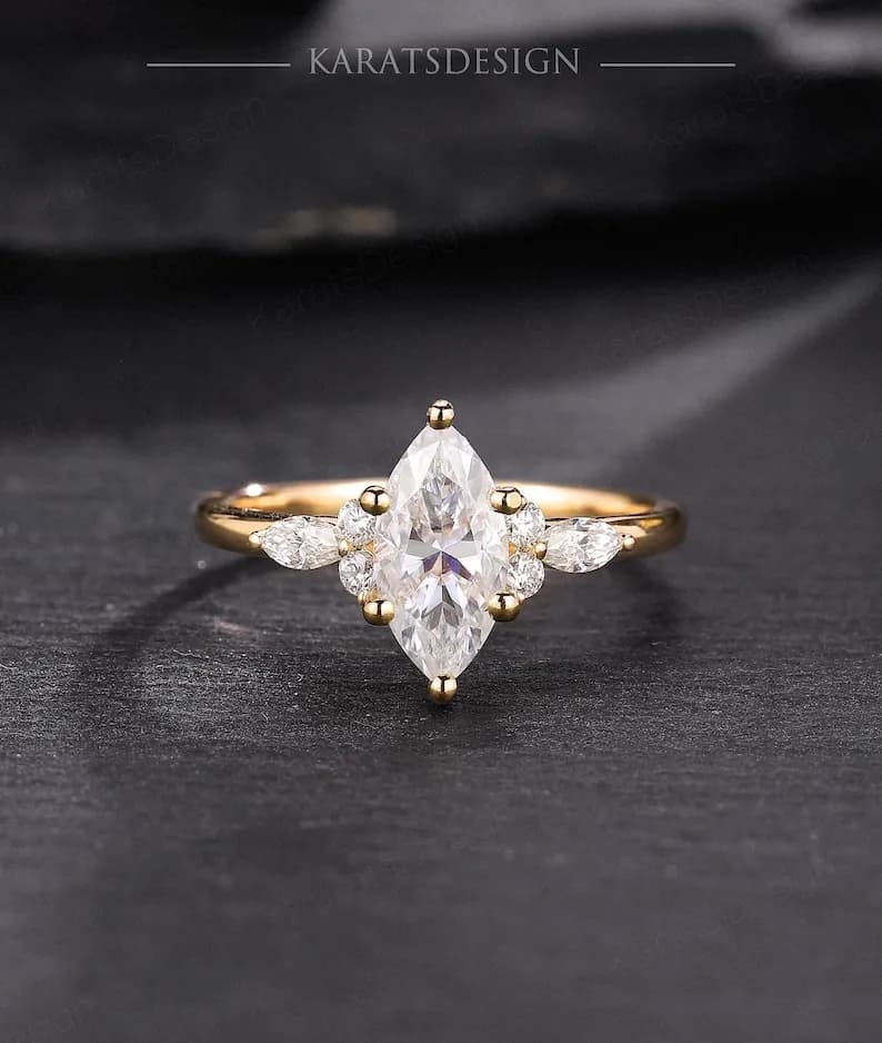 Gold engagement ring with a marquise-shaped diamond center stone and smaller pear-shaped diamonds on the band.