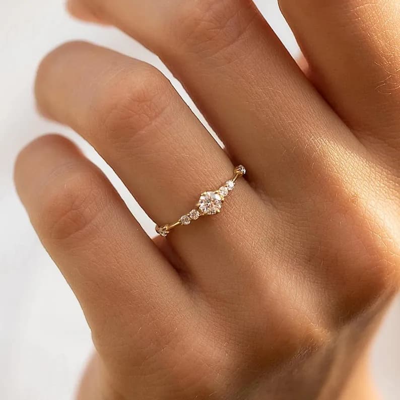 A delicate gold ring with a single round diamond and smaller diamonds set in a curved line.