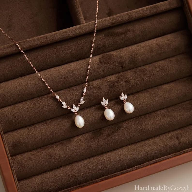 Dainty Freshwater Pearl Jewelry Set with leaf-shaped accents and teardrop pearl pendant, displayed on a brown velvet surface.