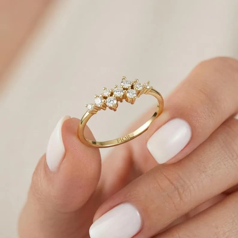 Gold ring with a cluster of small, clear gemstones, engraved with 'FIOR'.