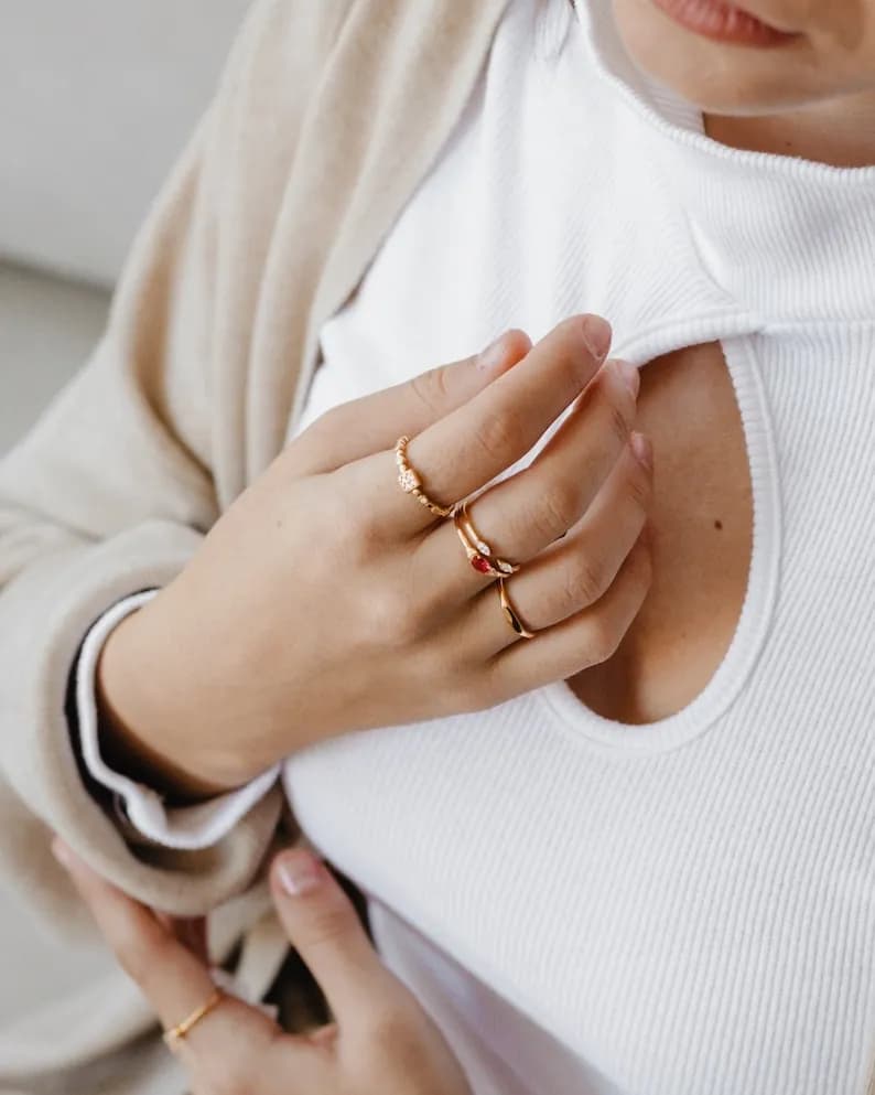 A hand wearing four gold rings stacked on the middle finger.