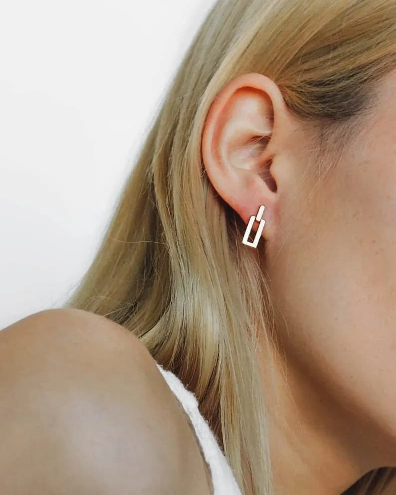 A pair of silver geometric earrings with a simple, modern design. The earrings are small and delicate, and they are perfect for everyday wear.