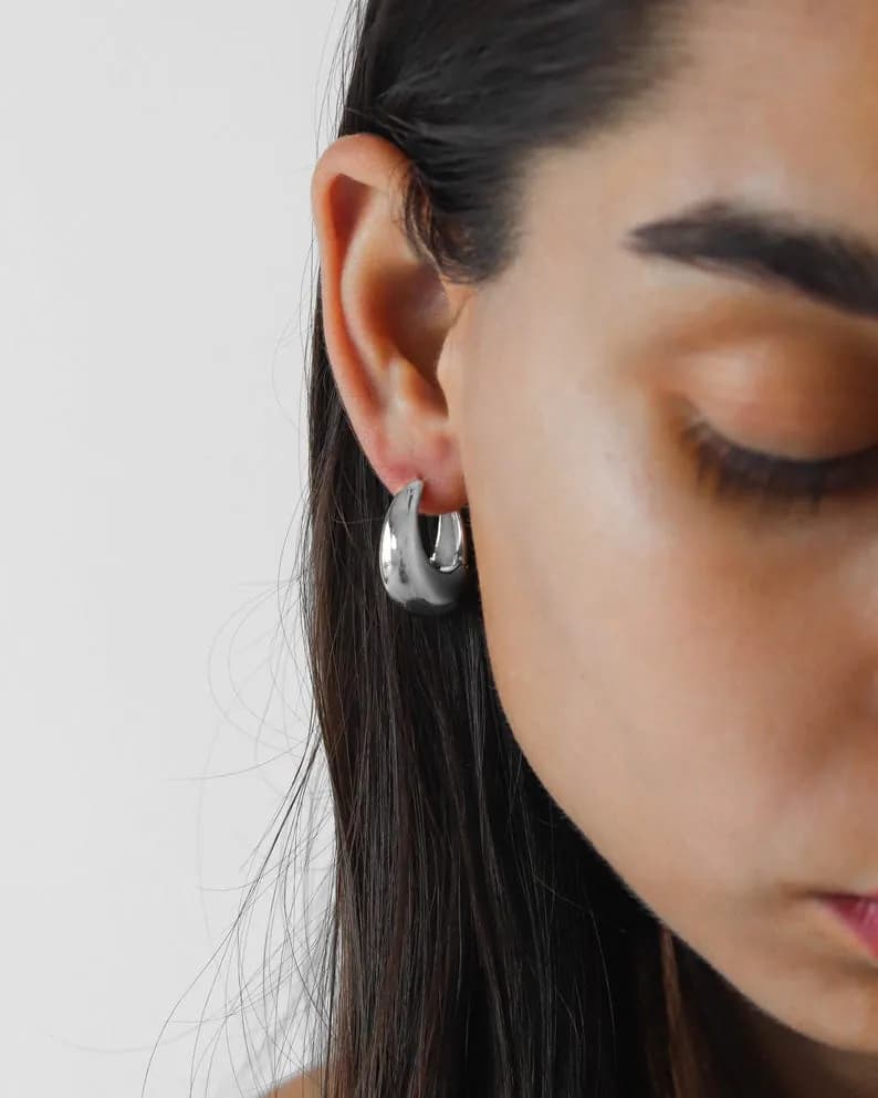 Silver hoop earrings worn in a person's ear.
