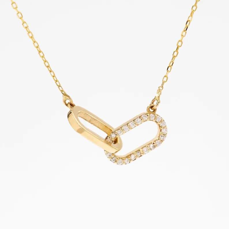 Gold chain necklace with a pendant featuring two interlocking oval shapes, one with a pave diamond setting.