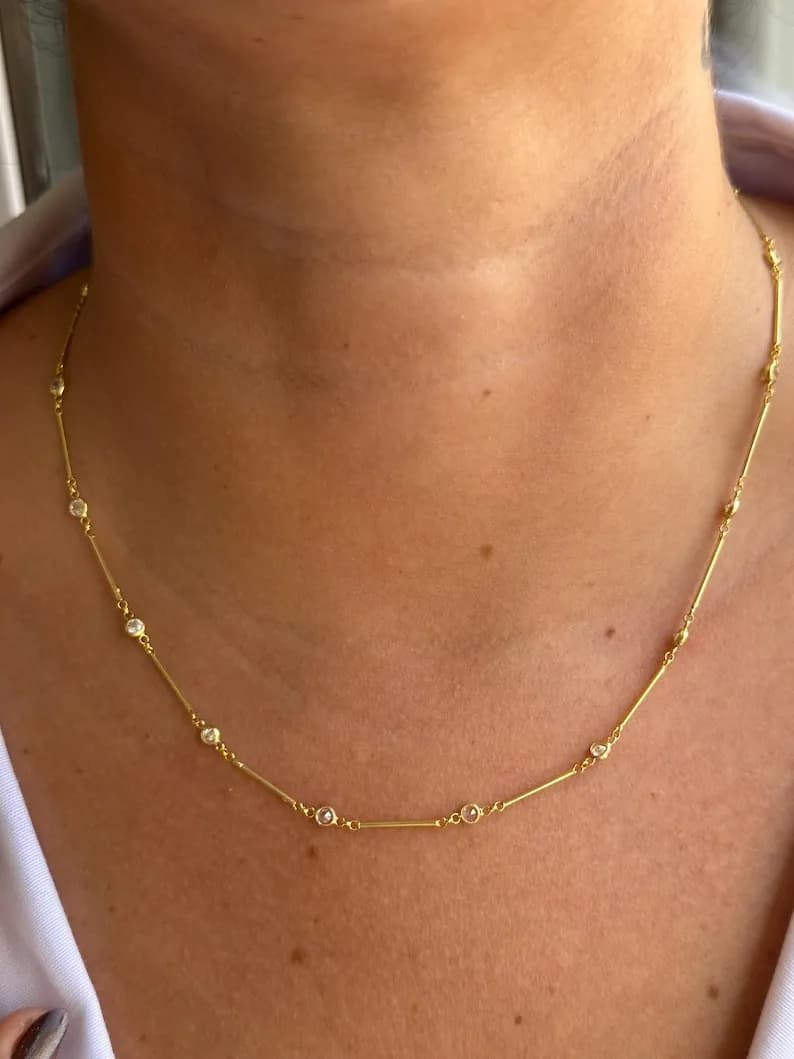 Delicate gold necklace featuring small, round, clear gemstones spaced along a thin chain, perfect for everyday wear or special occasions.